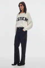 Jean flare de tiro medio, color negro con efecto gastado y estampado de lunares metalizados distribuidos por toda la prenda.