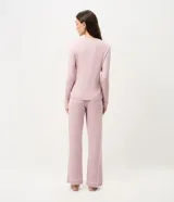 Pijama de dos piezas compuesto por una blusa de manga larga con cuello redondo y bolsillo frontal, y un pantalón recto con cintura elástica. Ambas prendas presentan detalles de piping en los bordes. Confeccionado en tejido de viscolycra suave y fluido.