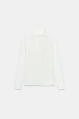 Camisa blanca de manga larga con cuello solapa y escote pico. Cierre frontal con botones.