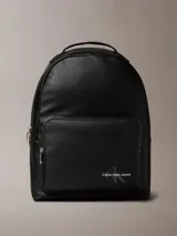 Mochila negra de cuero sintético con asa de mano y tirantes ajustables. Tiene un bolsillo frontal con cierre y el logo de Calvin Klein Jeans estampado en la parte inferior.