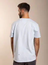 Remera de algodón color azul, de corte clásico con cuello redondo y manga corta. Presenta un pequeño bordado distintivo de un ave en el pecho.