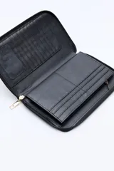 Billetera capitoneada en símil cuero color negro, con pespuntes en diagonal y cierre perimetral. Cuenta con un logo metálico dorado en el frente.