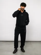 Pantalón jogger de felpa sin frisa, color gris claro melange, con logo bordado de Umbro en azul oscuro en el muslo izquierdo y puños elásticos en los tobillos.