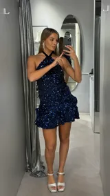 Vestido corto de fiesta con lentejuelas azul marino, diseño con cuello halter y falda con volados escalonados.