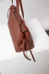 Cartera negra de cuero con forma alargada, cierre metálico color níquel y bolsillo interno con cierre. Interior 100% algodón.