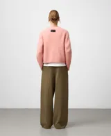 Sweater de punto color rosa, de corte corto con cuello redondo y mangas largas. Presenta acabados en canalé en cuello, puños y bajo. Confeccionado en una mezcla de lana merino y alpaca que ofrece una textura suave y abrigada.