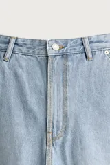 Pantalón jeans relaxed fit de mezclilla azul oscuro, con estilo carpintero que incluye bolsillos laterales y presillas de herramientas. Cuenta con costuras pespuntadas en contraste y cierre frontal con botón y cremallera.