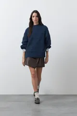 Sweater de punto color marrón chocolate, con cuello redondo, mangas largas abullonadas y puños ajustados. Presenta un diseño de textura acanalada horizontal y silueta relajada.