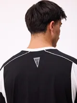 Remera de corte holgado en color negro con detalles en blanco en el cuello y paneles laterales. Presenta logo de la marca estampado en el centro del pecho.