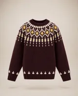 Buzo tejido en lana merino con diseño nórdico, de color bordó con guardas decorativas en tonos manteca y mostaza en el cuello y puños. Presenta un corte clásico de cuello redondo y mangas largas.