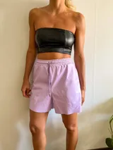 Short lila de cuero sintético con cintura elástica y cordón ajustable.