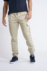 Pantalón cargo color beige de corte slim, con cintura elástica y cordón de ajuste. Presenta bolsillos laterales tipo cargo y puños elásticos en los tobillos.