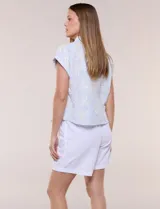 Camisa celeste con bordado floral en color crudo, de corte semi holgado, cuello camisero, manga corta japonesa con dobladillo y cierre frontal de botones.