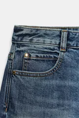 Jeans de tiro medio con diseño de cinco bolsillos, pernera holgada y bajo con vuelta. Cierre frontal con cremallera y botón.