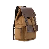 Mochila de tela canvas color negro con solapa y detalles en cuero sintético marrón. Presenta un cierre superior tipo marinero con cordón ajustable, solapa principal con correas y hebillas, y un bolsillo frontal con solapa. Posee bolsillos laterales con cierre metálico y correas de hombro ajustables.