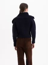 Cardigan de tejido tipo corderito en color azul marino, con cuello alto, cierre frontal con tirador metálico en forma de fresa y mangas largas.