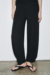 Pantalón de tiro alto con pierna ancha y cintura elástica ajustable. Presenta un diseño de corte holgado con costuras verticales frontales que definen su silueta.