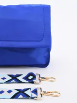 Bandolera roja de tela acolchada con solapa y cierre magnético. Incluye correa de hombro ajustable y extraíble, y detalle de borla de cordones de colores.