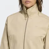 Campera Adidas Firebird color beige, con cierre frontal y cuello alto. Presenta las tres tiras características de la marca en las mangas y logo bordado en el pecho. Corte por encima de la cintura.