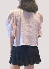Blusa de lino color rosado, con escote en V, mangas abullonadas 3/4 y cierre frontal con botones.