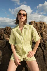 Camisa de manga corta oversize en lino rayado, con cuello camisero, cierre frontal con botones y bordado playero en el frente.