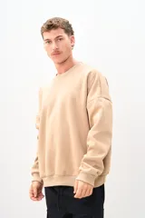 Buzo color beige de corte holgado, con cuello redondo y mangas largas.