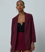 Blazer de sastrería color bordó, de corte oversized y largo, confeccionado en crepé. Presenta solapas clásicas, bolsillos frontales y detalle de pliegues en los puños.
