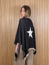 Ruana de punto color negro con detalle de estrella blanca en la espalda y bordes en tono tostado.
