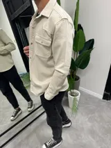 Sobrecamisa de gabardina color beige con cierre frontal de botones metálicos a presión, dos bolsillos frontales con solapa y diseño de canesú estilo western.