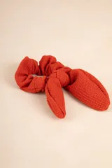 Gomita de pelo tipo scrunchie color verde salvia, con textura arrugada y moña con forma de orejas de conejo.