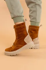 Bota de caña media color marrón óxido, confeccionada en cuero gamuzado. Presenta cierre frontal con cremallera, suela track color beige y detalle de pieza de cuero en la parte trasera del tobillo.