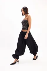Pantalón negro de corte amplio, con cintura elástica fruncida y diseño abombacho con volados en los tobillos.