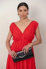 Vestido largo rojo de corte griego, sin mangas, con escote en V profundo, falda amplia y detalles de encaje.