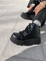 Botas negras de ecocuero con detalle de cadena en la parte delantera y taco de 6cm.