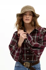 Camisa de algodón con estampado de cuadros en tonos bordó, verde y beige. Presenta mangas largas abullonadas con puños fruncidos, cuello camisero clásico y botones de nácar.