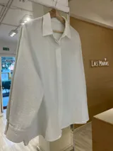 Camisa oversize color verde militar con finas rayas verticales de lurex, cuello camisero y mangas largas con puños anchos.