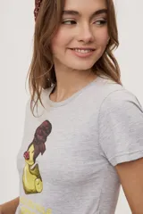 Remera blanca de manga corta, con estampa frontal de un pato de hule con turbante y labios pintados, acompañada de la frase "In all else fails, denial".