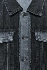 Cazadora de denim negra con cuello solapa, manga larga y bolsillos con solapa en el pecho. Presenta un detalle de tejido a contraste en color denim claro en el delantero y la espalda. Cierre frontal con botones metálicos.