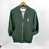 Campera bomber verde con textura tipo waffle, cierre frontal y logo pequeño bordado en blanco en el pecho.