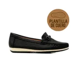 Mocasín casual negro de textura acanalada, con capellada perforada, detalle de hebilla metálica en el empeine y suela blanca con base negra.