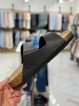 Sandalias de dos tiras negras con hebillas metálicas ajustables, plantilla anatómica y suela plana.