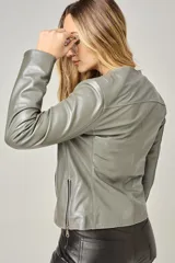 Campera clásica de cuero ovino color beige claro, con cuello a la base, cierre frontal y bolsillos laterales con cierre. Presenta costuras verticales que estilizan la silueta.