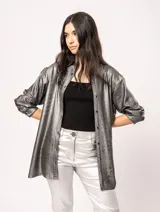 Camisa oversized con terminación metalizada color gris plomo. Tiene botones a tono en el delantero, largo por debajo de la cadera y tajos a los costados.