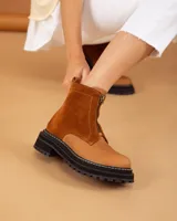 Botas de caña corta color beige, confeccionadas en cuero con textura granulada. Presentan cierre frontal central, suela track negra de goma con costuras blancas visibles y tirador en la parte trasera.