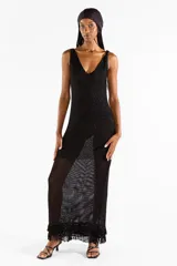 Vestido largo negro de punto abierto con sutil brillo de lúrex, escote en V y detalles de flecos en el ruedo.