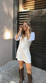 Vestido corto color crudo, con escote en V y mangas 3/4 abullonadas con detalles de calado.