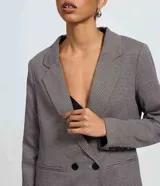 Blazer sastre de corte regular con estampado de cuadros, solapas clásicas y cierre frontal con dos botones. Presenta bolsillos embutidos y un diseño estructurado.