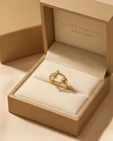 Anillo de acero quirúrgico dorado con diseño ovalado y aplique transversal, decorado con circones en su estructura.