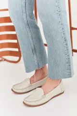 Mocasines de cuero color dorado con acabado texturizado, diseño clásico de punta redondeada y costuras visibles en el empeine. Cuentan con suela plana y flexible.
