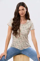 Remera de manga corta con cuello redondo, confeccionada en algodón con estampa de diseño floral en tonos rosados y verdes sobre base beige.